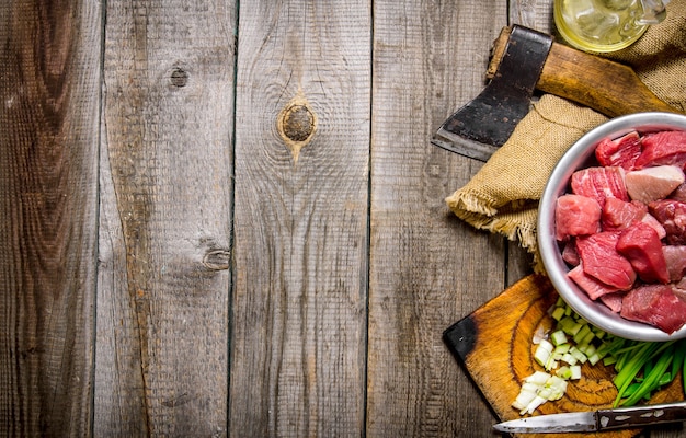 Gehacktes rohes Fleisch mit frischen Zwiebeln und einer Axt auf einem alten Stoff.