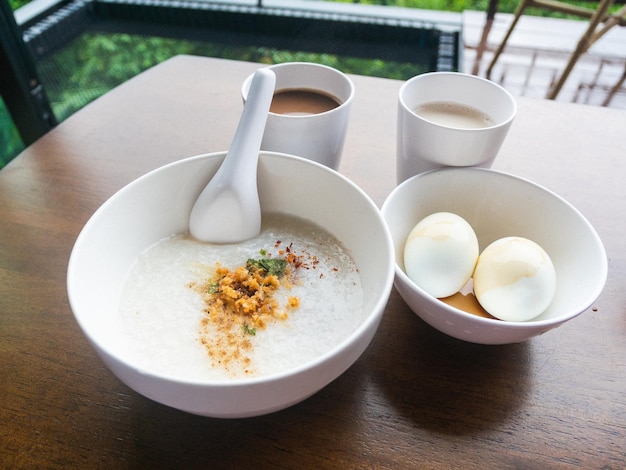 Foto gehacktes schweinefleisch congee mit weich gekochtem ei in schüssel auf holztisch.