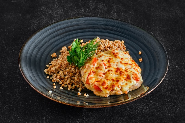 Gehacktes Schweinefleisch, gebacken mit Käse und Tomaten, serviert mit Buchweizenbrei