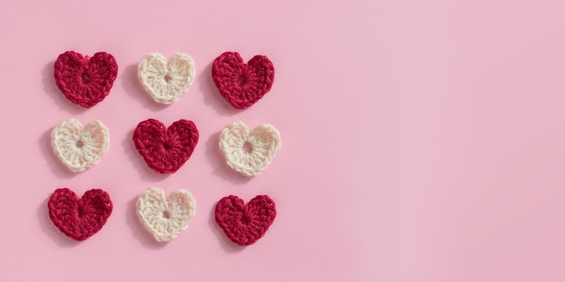 Gehäkelte Amigurumi rosa rote und weiße Herzen auf einem rosa Hintergrund Valentinsmuster-Banner