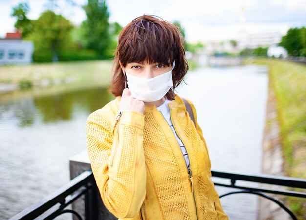 Geheimnisvolle nachdenkliche nicht identifizierte Frau geht im Park in einer Schutzmaske an einem sonnigen warmen Sommertag