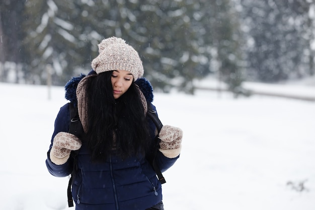 Geheimnisvolles, nachdenkliches Mädchen im Winter gegen auf Schnee und langen schneebedeckten Tannen