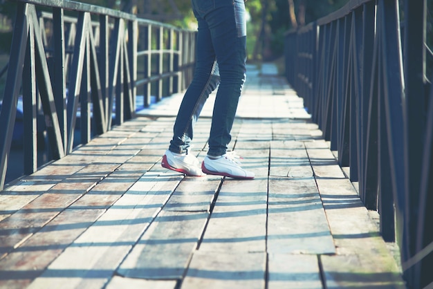 Gehende Damenjeans und Schuhe mit Sonnenlicht