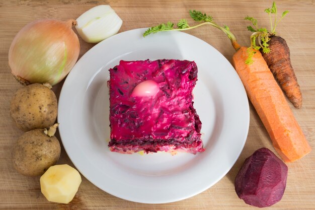 Gekleideter Hering oder Hering unter einem Pelzmantel. Traditionelle russische Küche. Schichtsalat aus gewürfelten eingelegten Heringen, bedeckt mit Schichten von gekochtem, geriebenem Gemüse und Mayonnaise.