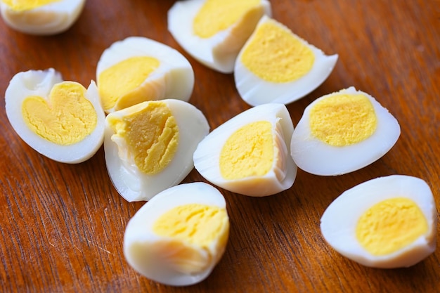 Gekochte Eier essen Wachteleier auf hölzernen Frühstückseiern mit frischen Wachteleiern und Gemüsesalat auf Tischhintergrund