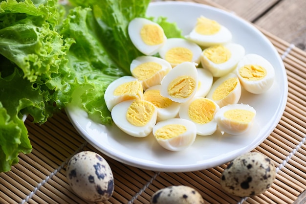 Gekochte Eier essen Wachteleier auf weißem Teller Frühstückseier mit frischen Wachteleiern und Gemüsekoriander auf Holztischhintergrund