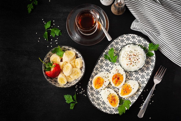 Gekochte Eier mit Joghurt, Paprika, Petersilie und Bananendessert Gesunde Ernährung zum Frühstück Draufsicht flach gelegt