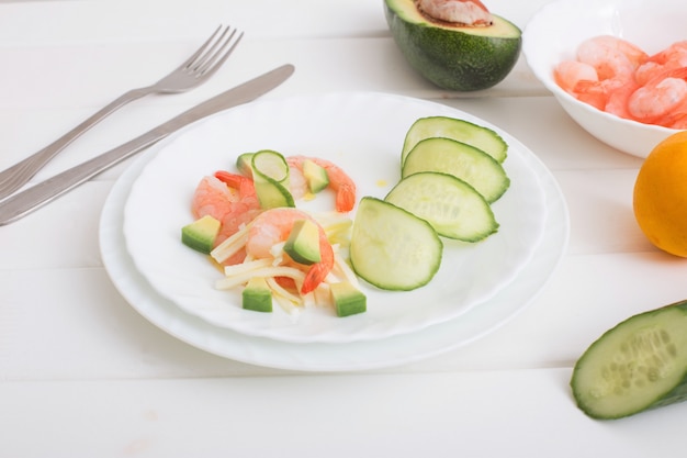 Gekochte Garnelen mit Avocado und Mozzarella auf weißem Holztisch