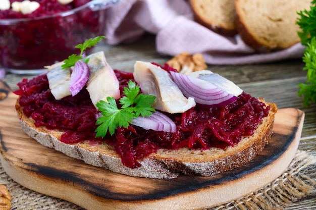 Gekochte geriebene Rübenstücke Hering rote Zwiebeln Nüsse auf Vollkornbrot