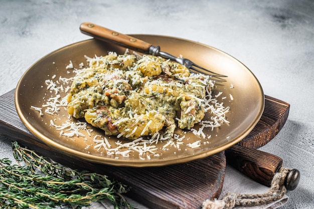 Gekochte Gnocchi-Kartoffelnudeln mit Spinat und Parmaschinken auf dem Teller. Weißer Hintergrund. Ansicht von oben.