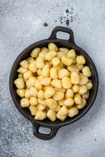 Gekochte Gnocchi mit Butter und Pfeffer. Grauer Hintergrund. Ansicht von oben.