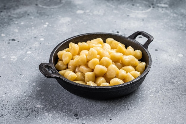 Gekochte Gnocchi mit Butter und Pfeffer. Grauer Hintergrund. Ansicht von oben.