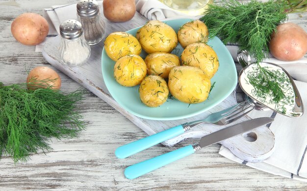 Gekochte kartoffeln auf platte auf holzbrett in der nähe von serviette auf holztisch