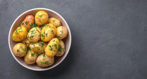 Gekochte Kartoffeln mit Dill und Butter Nahaufnahme auf dunklem Hintergrund