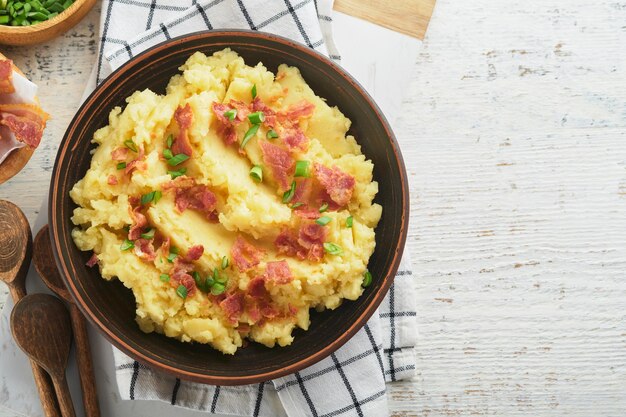 Gekochte Kartoffelpüree Speck-Kartoffelpüree mit Frühlingszwiebelpfeffer und Cheddar-Käse in Schüssel auf hellen alten Holzhintergründen Köstliche cremige Kartoffelpüree Ansicht von oben