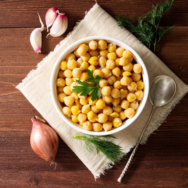 Gekochte Kichererbsen auf Schüssel auf dunklem Holztisch. Gesund, vegetarisch