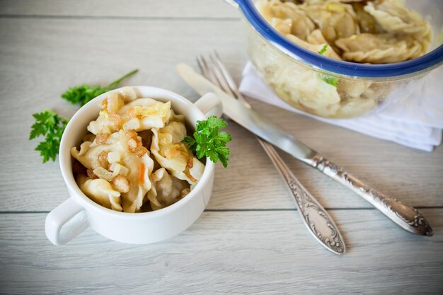 Foto gekochte knödel mit kartoffeln und röstzwiebeln in einer schüssel auf einem holztisch