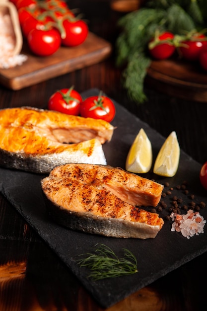 Gekochte Lachsringe sorgfältig auf einer Platte angerichtet. Zitrone und Tomaten im Hintergrund