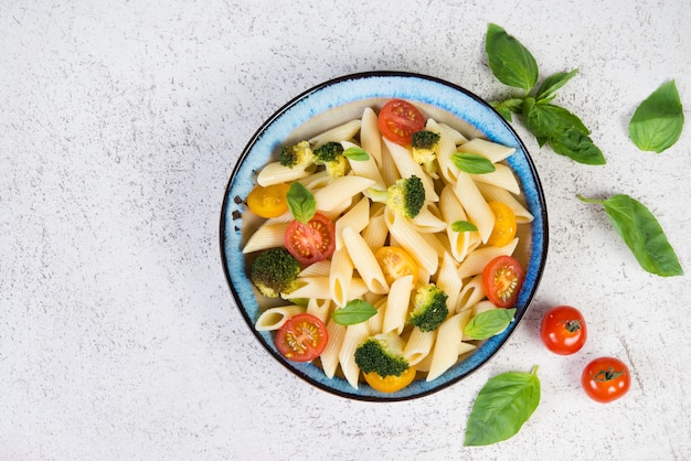 Gekochte Penne mit Gemüse, Brokkoli, Tomaten und frischen Kräutern.