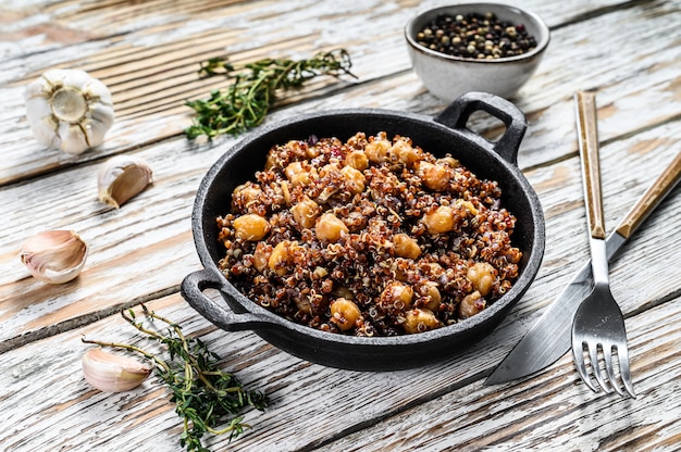 Gekochte Quinoa mit Kichererbsen in einer Pfanne. Gesundes Essen, Diät auf weißem Holz. Draufsicht