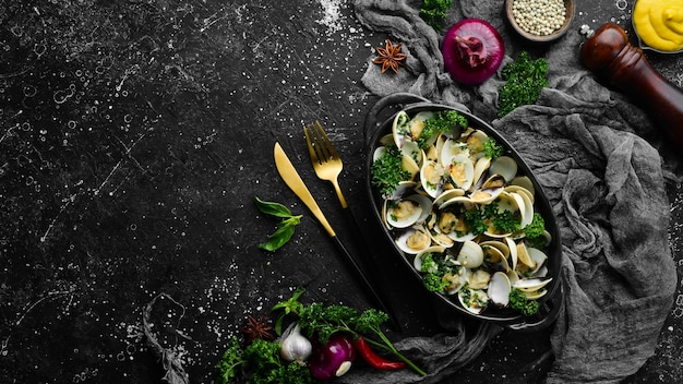 Gekochte Schalentiere in Schalen mit Knoblauch und Petersilie in einem schwarzen Teller Meeresfrüchte Draufsicht Freier Platz für Text