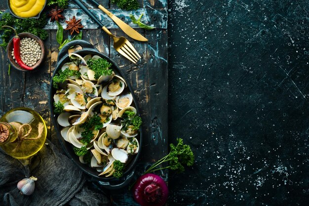 Foto gekochte schalentiere in schalen mit knoblauch und petersilie in einem schwarzen teller meeresfrüchte draufsicht freier platz für text