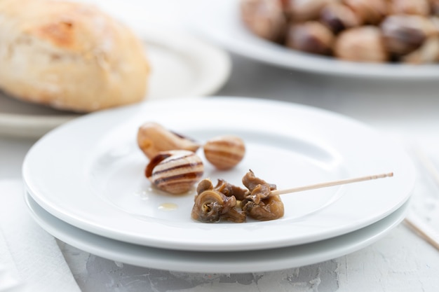 Gekochte Schnecken auf weißem Teller auf Keramik