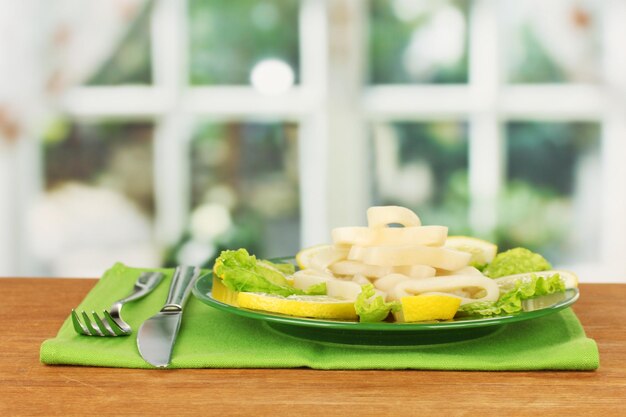 Gekochte Tintenfischringe auf Salat mit Zitrone auf dem Teller in Nahaufnahme