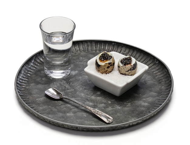 Gekochte Wachteleier mit Kaviar und einem Glas Wodka auf Weiß