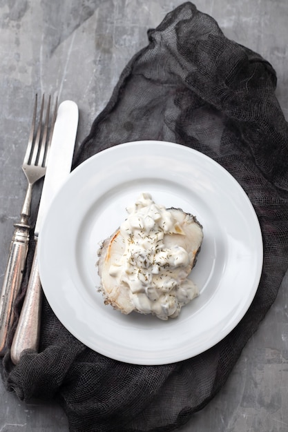 Gekochter Fisch mit Sauce auf weißem Teller