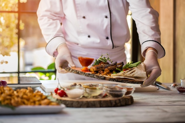 Gekochtes Fleisch mit Kräutern. Chef hält Teller. Saftiges gegrilltes Schweinefleisch mit Gemüse. Delikatesse aus der Speisekarte des Restaurants.