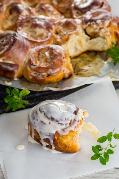 Foto gekochtes gebackenes süßes cinnabon mit sahne in backpapier auf einem holztisch