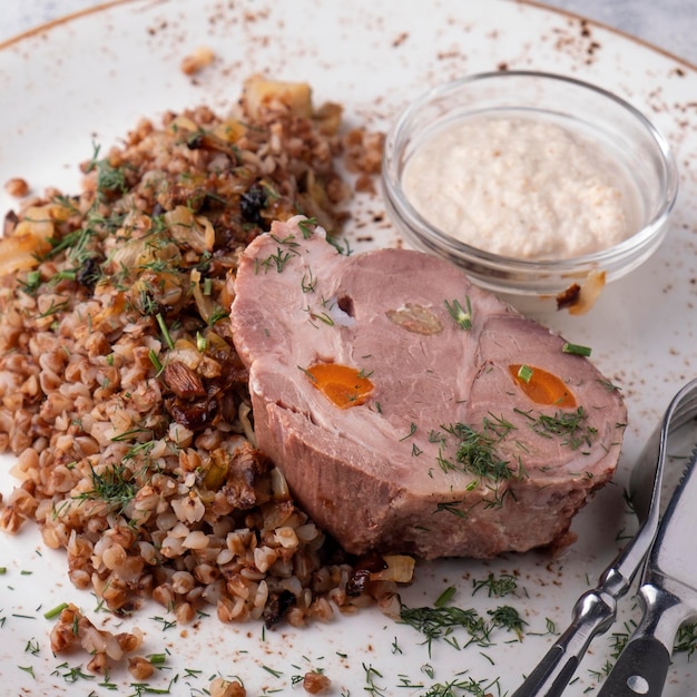 Gekochtes Schweinefleisch mit Buchweizenmüsli serviert mit Gabel und Messer Closeup