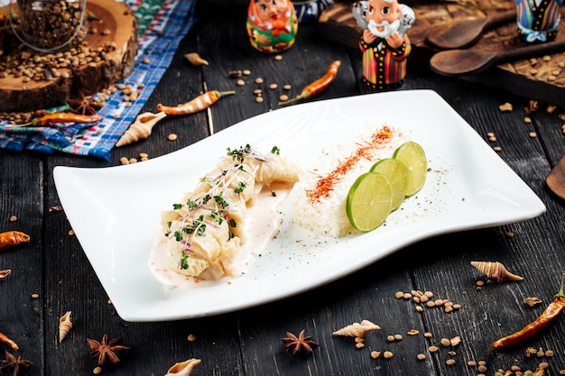 Gekochtes weißes Fischfilet mit Reis auf dem schwarzen Holztisch