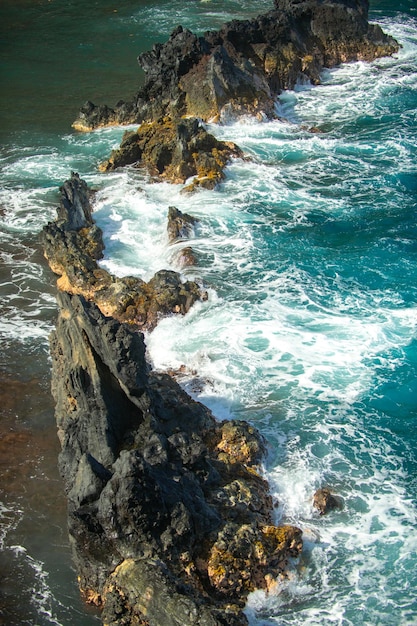 Gekühlte Lava und Meereswellen Blick auf Meereswellen, die Felsen auf den Strandwellen und Felsen treffen