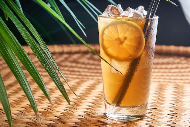 Gekühlte Sommergetränke mit frischem Orangensaft und Cola auf Korbtisch mit Blättern