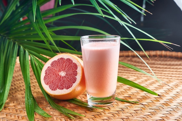 Gekühlte sommergetränke mit frischem rosa saft mit halber frucht auf weidenkorb mit blättern