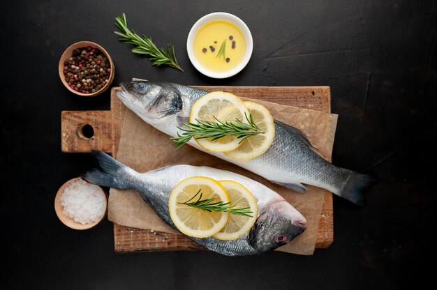 gekühlter roher Wolfsbarsch und Dorado-Fisch mit Zitrone und Rosmarin auf einem Steinhintergrund