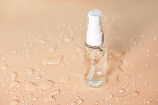 Foto gel de aloe cosmético transparente en una botella de vidrio con fondo beige de bomba con gotas de agua gel hidratante para el cuidado de la piel producto de belleza facial transparente sin marca
