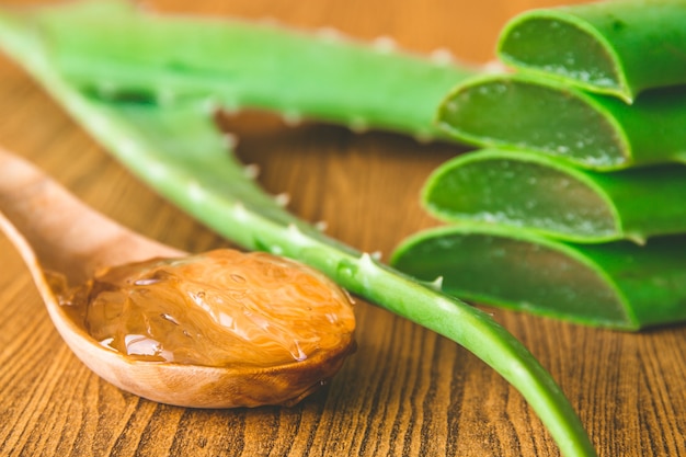 Gel de Aloe vera en cuchara de madera con aloe vera en mesa de madera. Enfoque selectivo