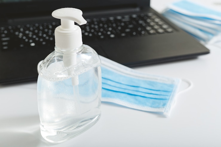 Foto gel antiséptico desinfectante para manos, máscara de protección respiratoria, máscara quirúrgica para protección contra virus en la computadora portátil. trabajo remoto, trabajo de oficina, freelance, trabajo desde casa. prevención de coronavirus covid-19.
