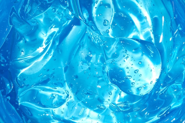 Gel cosmético ou fundo de textura de soro de geléia de beleza. Cenário de produto de colágeno azul transparente para cuidados com a pele. Desinfetante antibacteriano ou toner líquido e úmido manchado foto close up