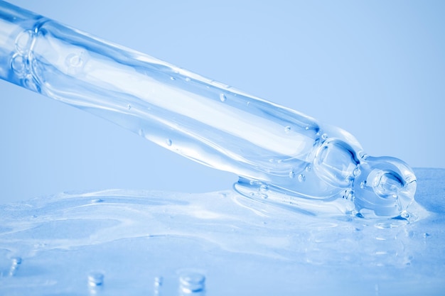 Gel cosmético transparente fluindo do conta-gotas e espalhado no fundo Sobre um fundo azul Ácido hialurônico toner gel creme Cosméticos