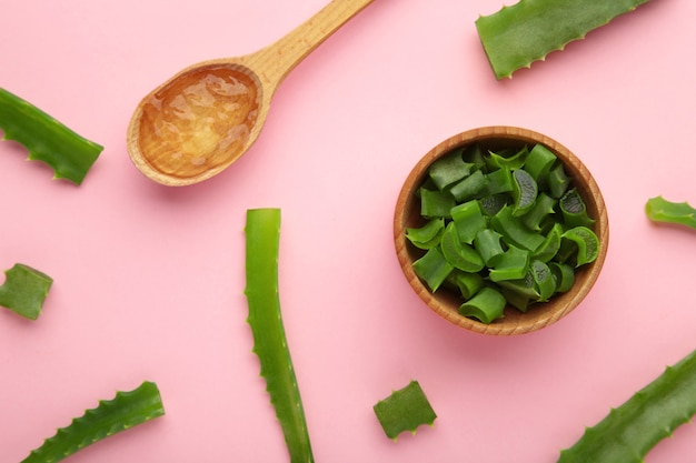 Gel de aloe vera na colher de pau com aloe vera no fundo rosa. Vista do topo.