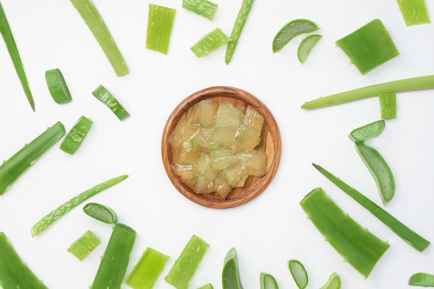 Gel de babosa em um copo com diferentes pedaços de planta em um fundo branco plano