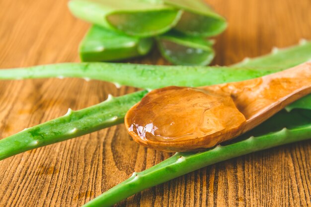 Gel de vera do aloés na colher de madeira com aloés vera na tabela de madeira. Foco seletivo