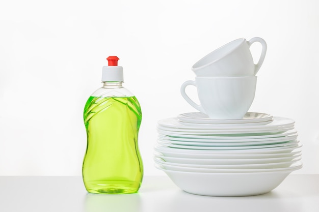 Gel para lavar platos verde y un juego de platos sobre un fondo claro