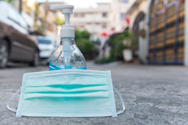 Gel de manos de alcohol etílico y mascarilla quirúrgica colocados en la calle frente a la casa, concepto de coronavirus, COVID-19