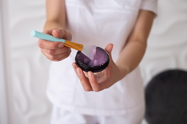 Gel rosa em um recipiente preto com espátula de plástico cosmetologista