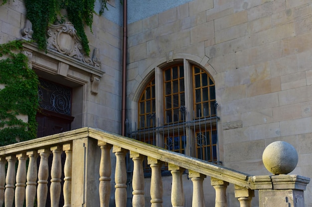 Geländer einer alten Steintreppe, halbrundes Fenster und massive Holztür, Polen, Posen